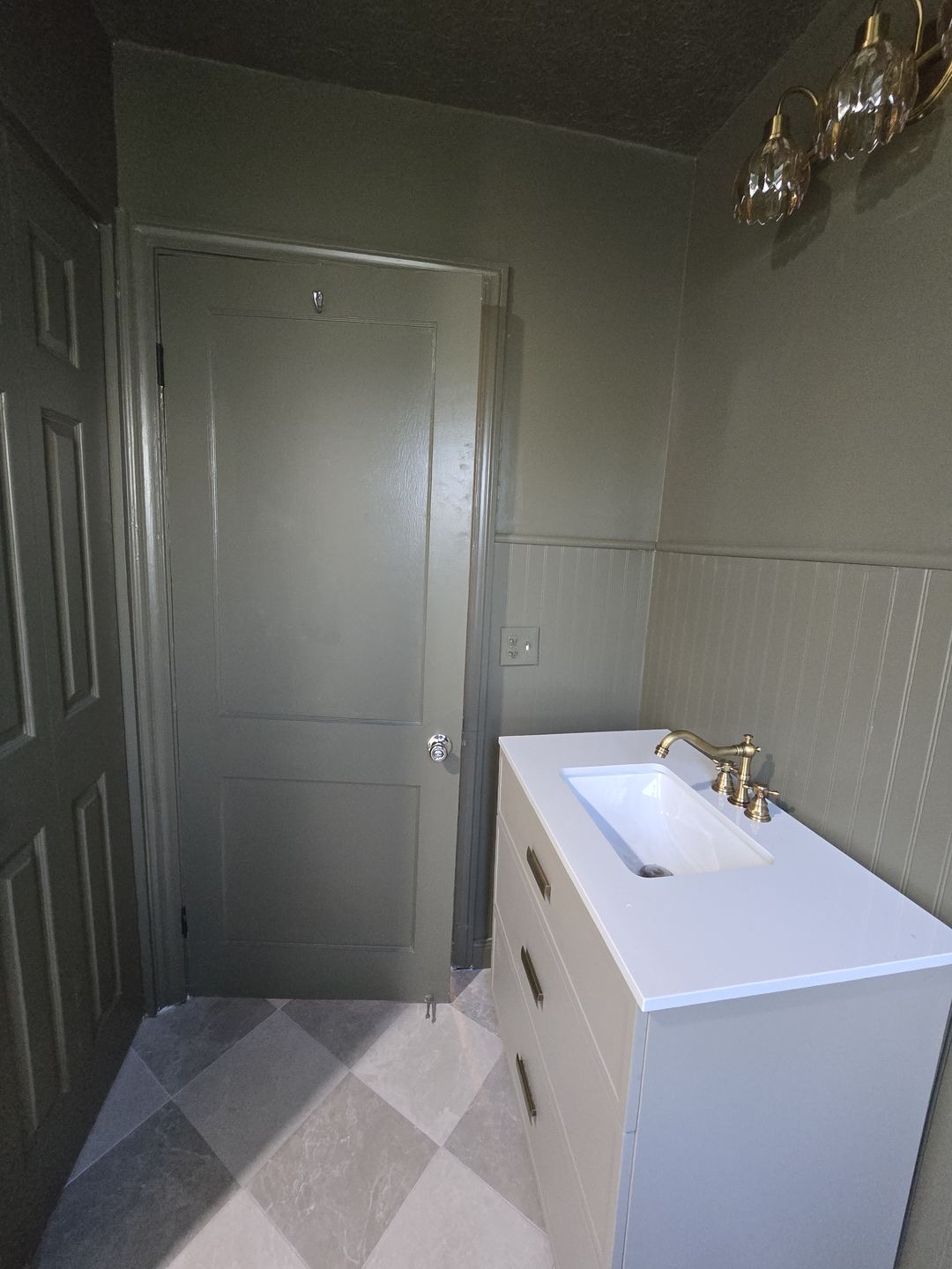 Bathroom door, frame and trim painted the same olive green as the walls